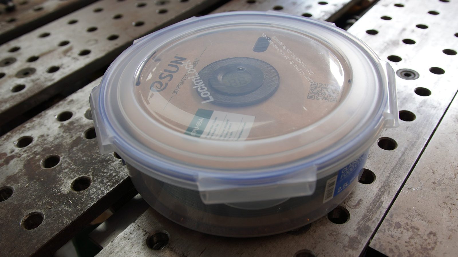 A sealed Lock and Lock food container on a welding bench with a filament spool visible inside.