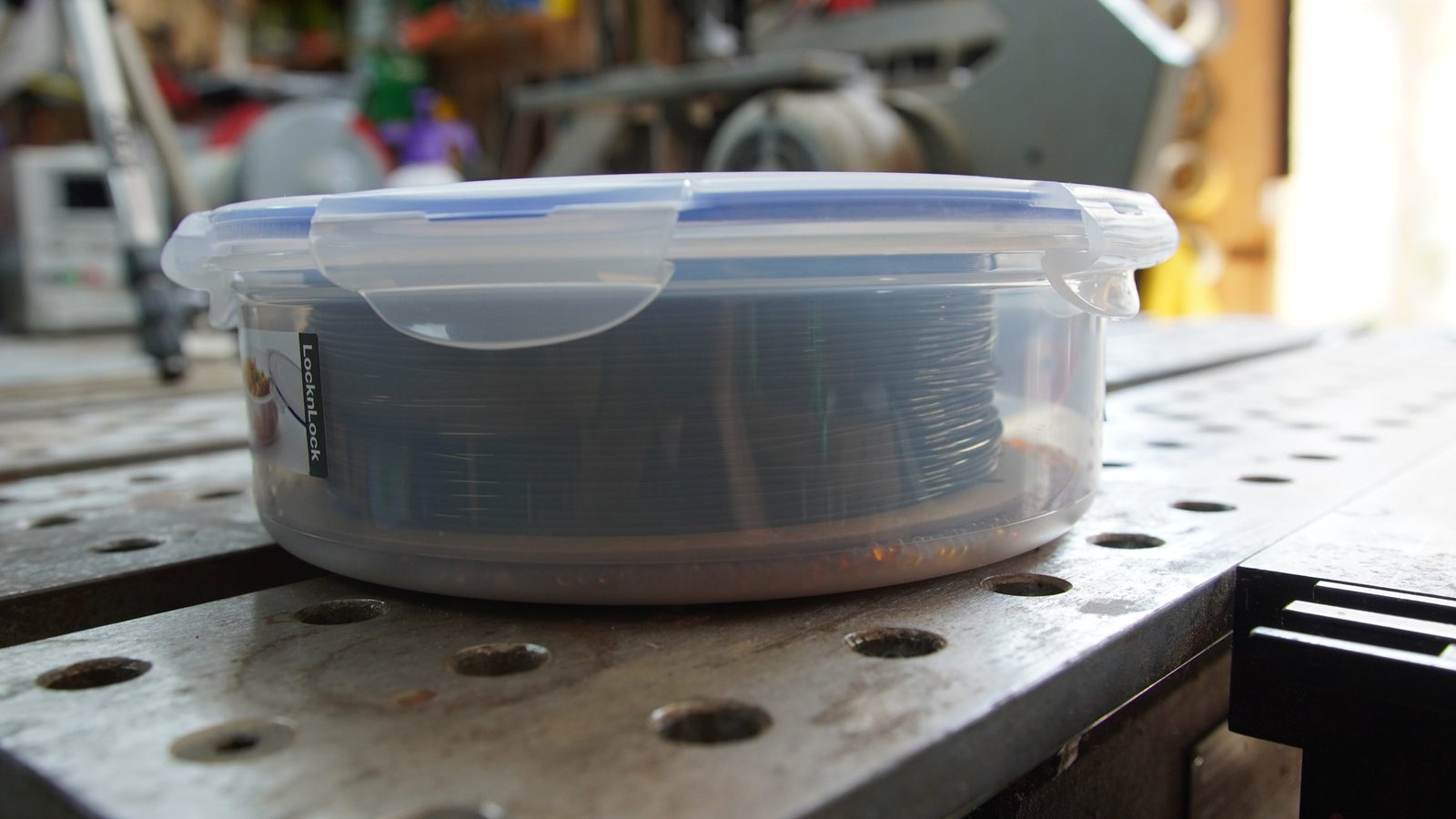 Side view of the food container showing the wound filament spool filling it almost exactly.