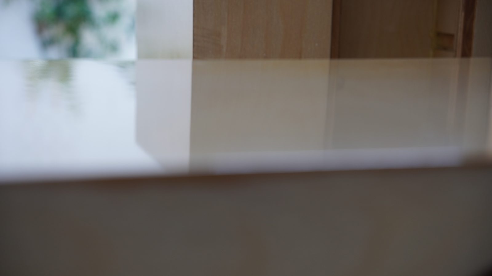 Close view of the glossy clear finish reflecting a window on the speaker side panel.