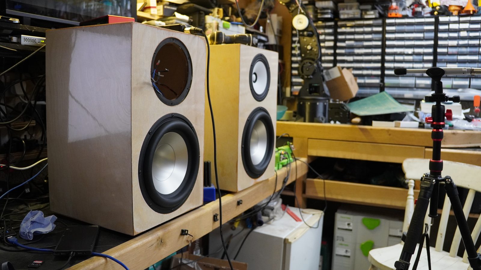 Pair of plywood active speakers with drivers fitted on the workshop bench.