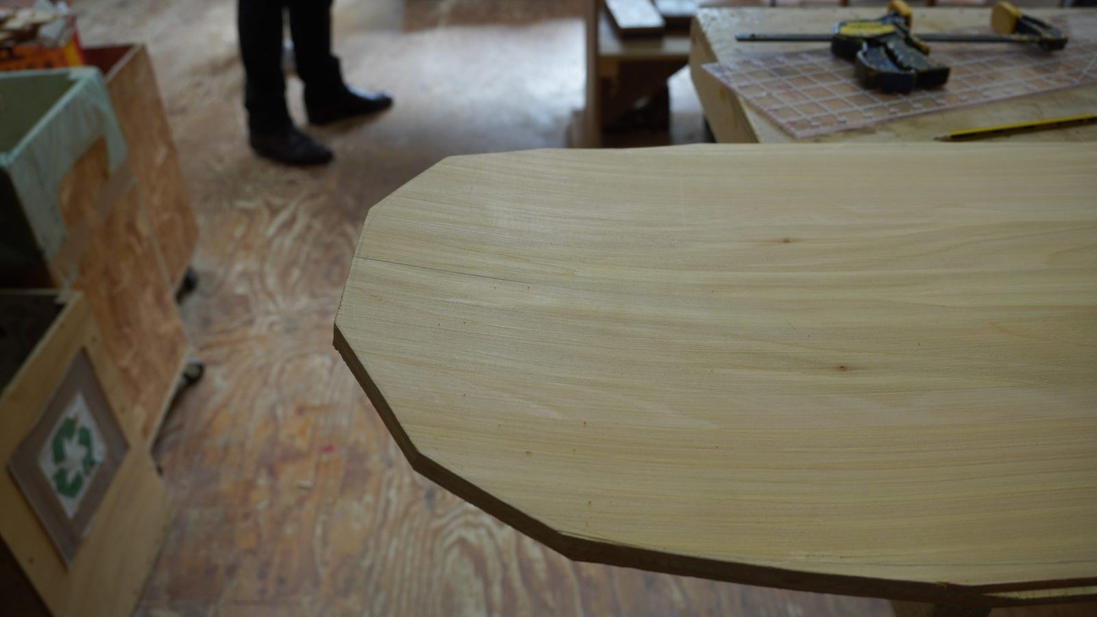 Rounded wooden belly board outline on a workshop floor.