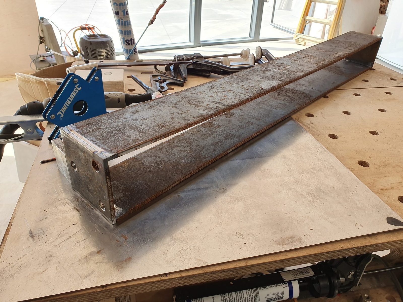 Weathering steel box section on a workbench during fabrication.