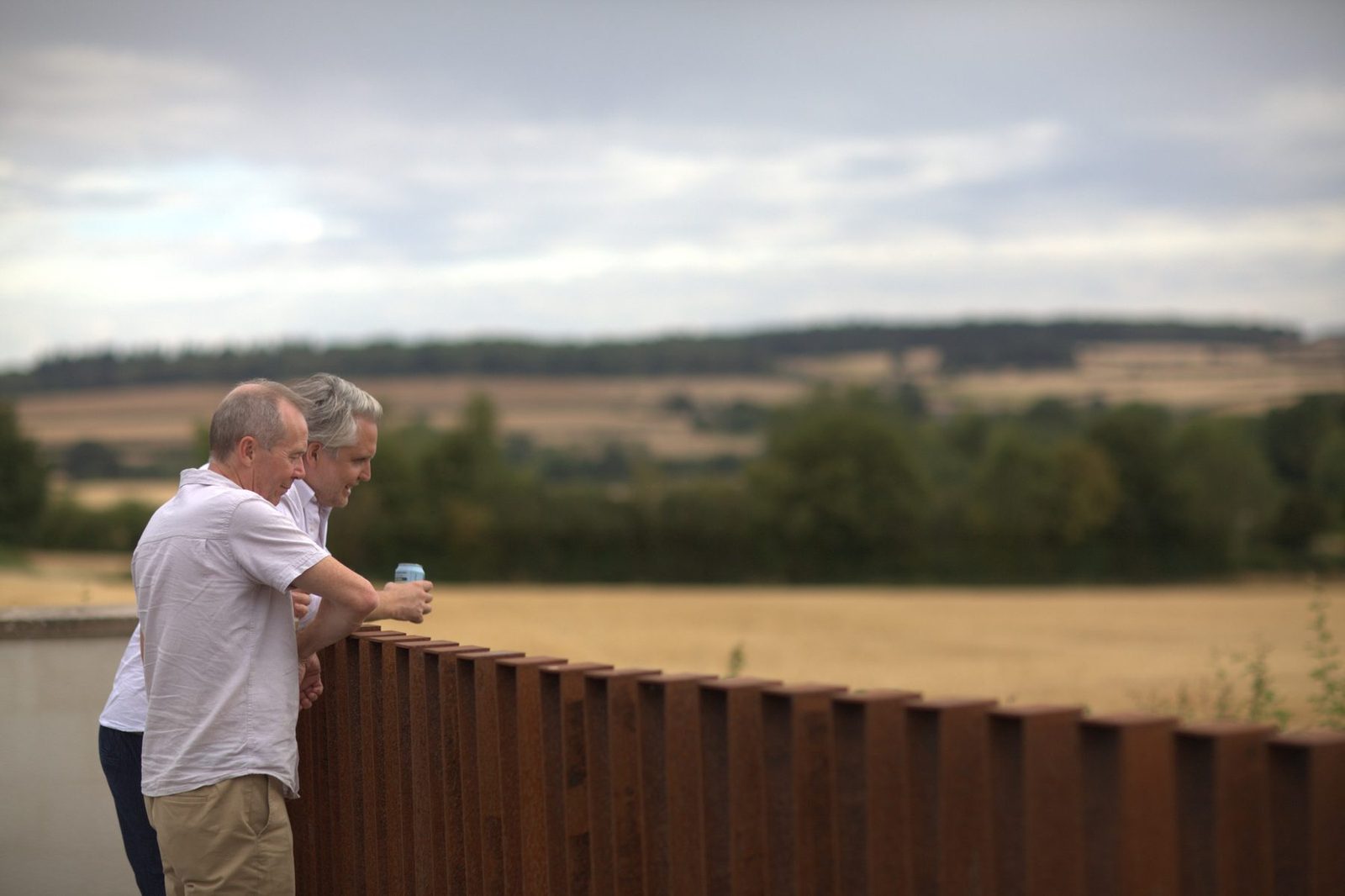 People leaning on the completed corten balustrade and looking across the countryside.