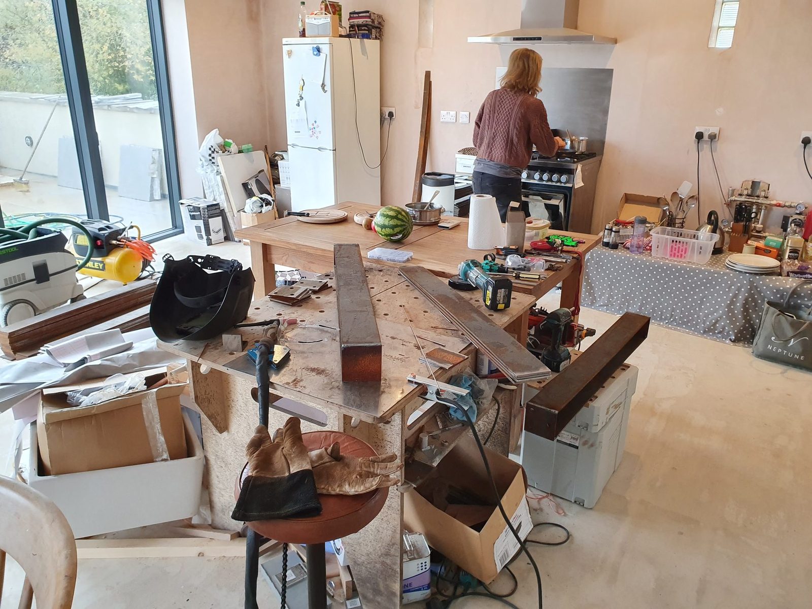 A welding table with corten steel parts in an unfinished kitchen.