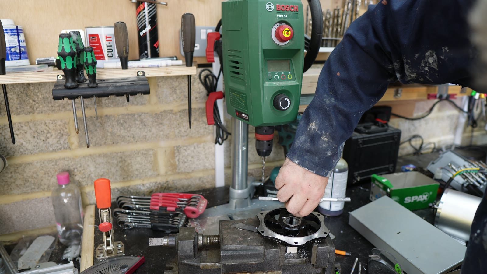 A drill press being used on a drift trike component in the workshop.