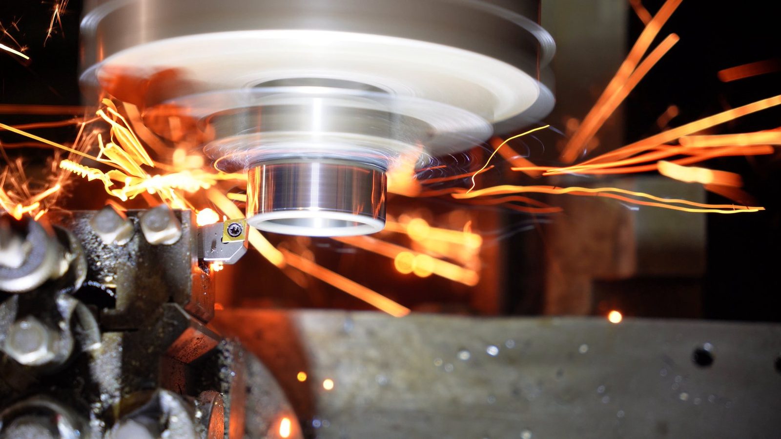Bright orange sparks from hardened steel being machined on a lathe.