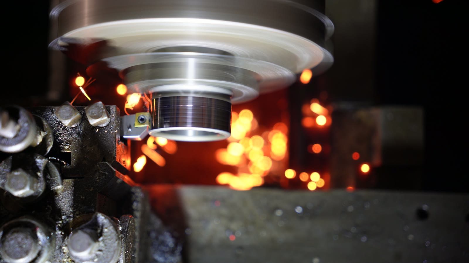 A bright burst of orange sparks trailing away from the lathe tool.