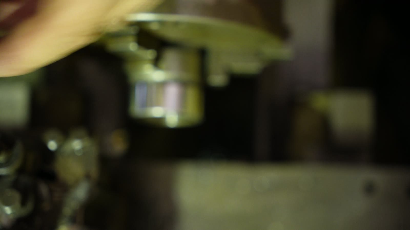 Close view of the lathe tool and spinning workpiece under green workshop light.