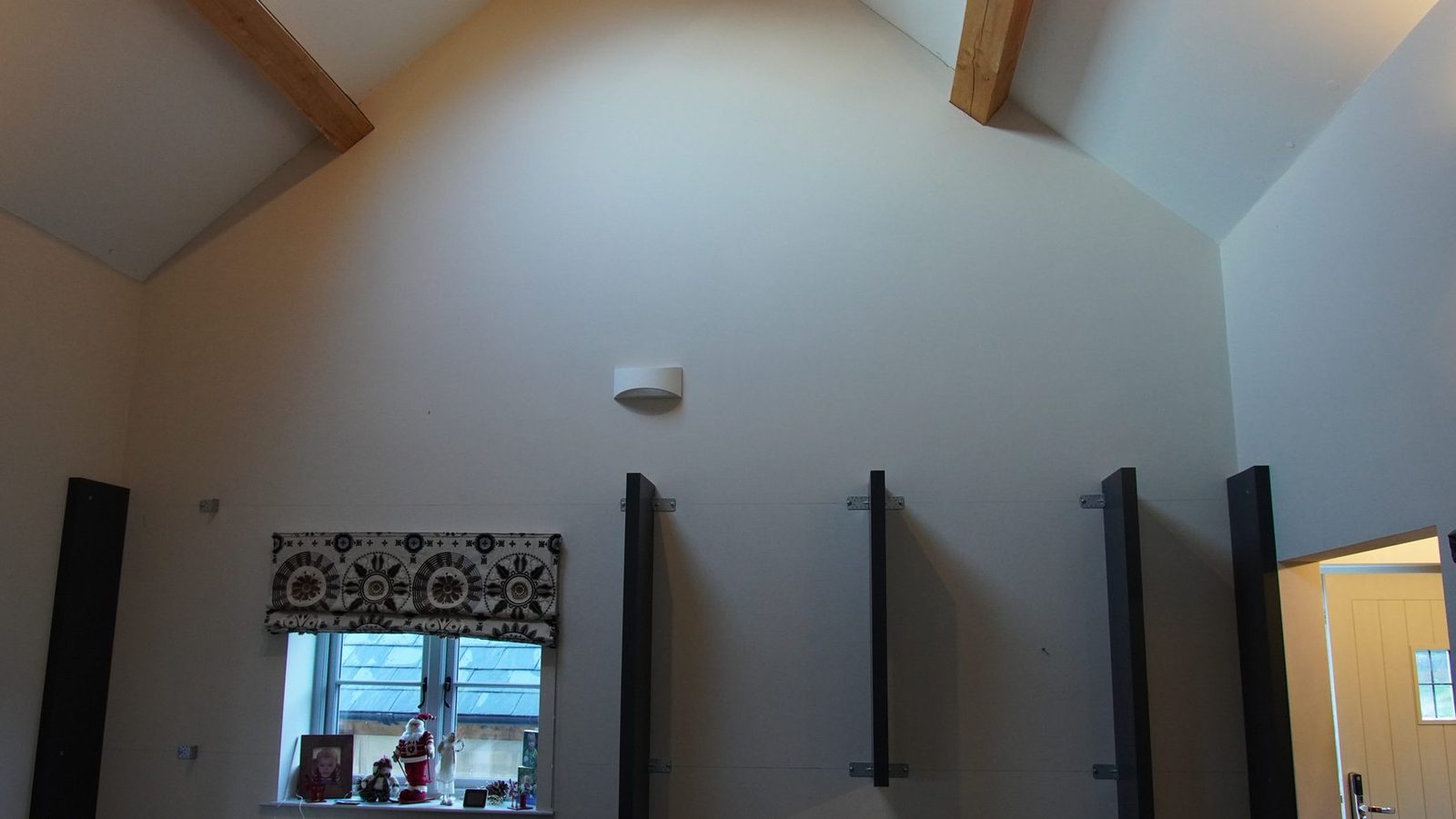 First dark vertical bookcase uprights fitted to the wall around a window.