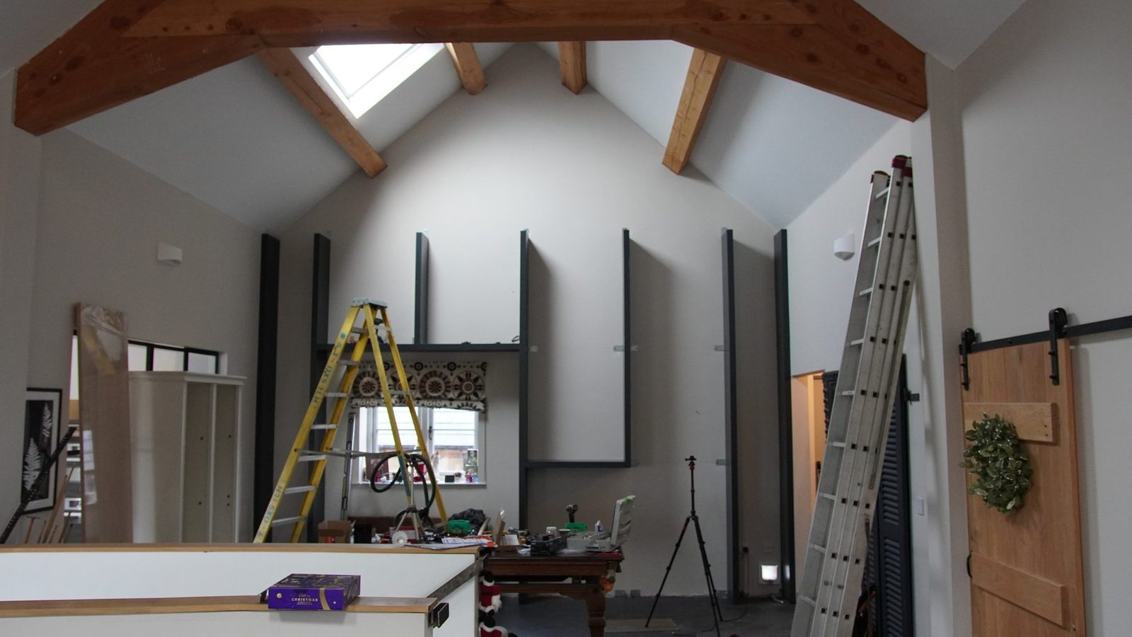 Bookcase wall frame in progress with ladders and tools in the room.