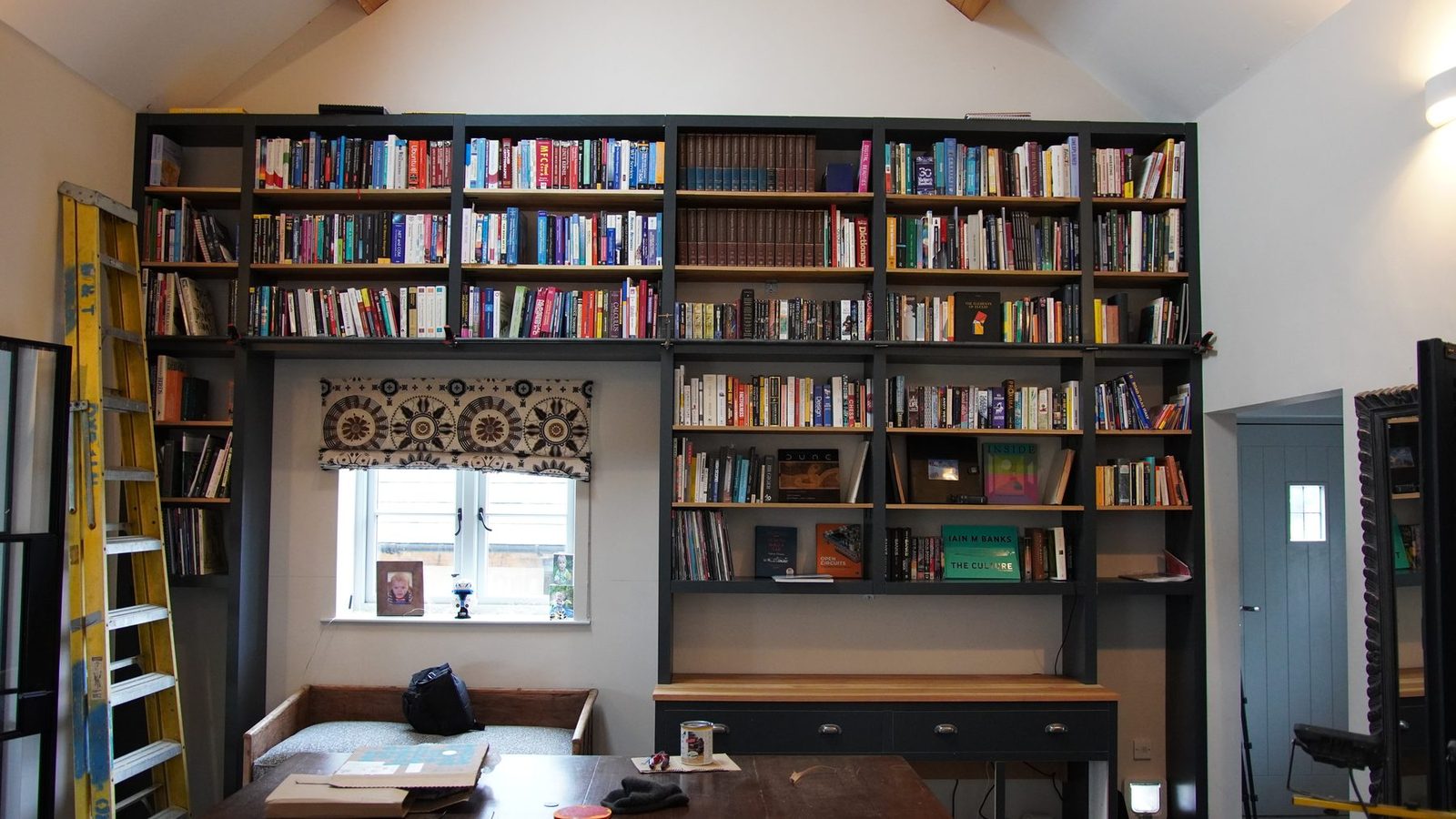 A wall-sized bookcase filled with books, with a rolling ladder.