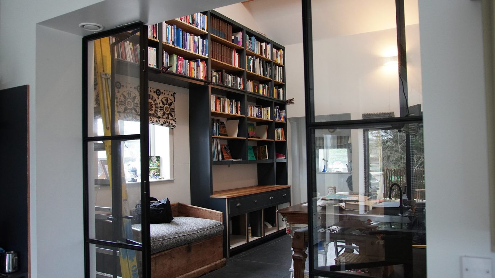Custom bookcase seen through black-framed glass doors.