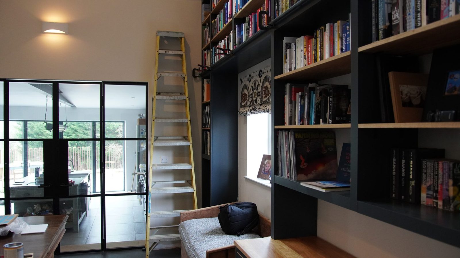 The bookcase in the wider room with glass doors and seating.