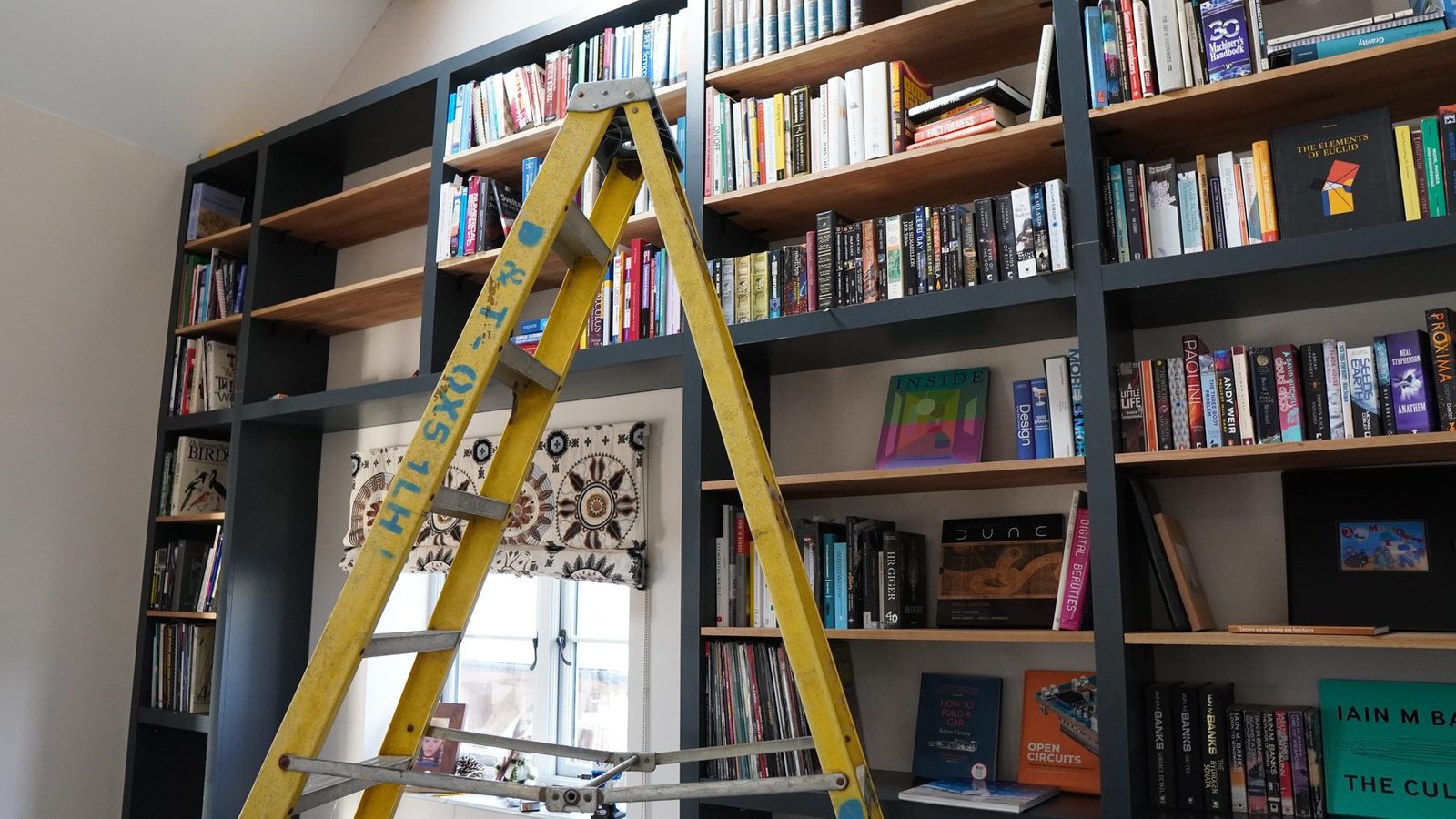 Rolling ladder positioned on rails in front of the bookcase.