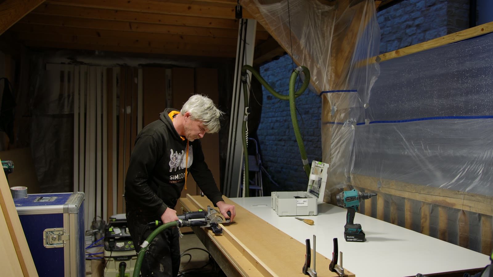 Daniel working at a bench with timber parts during the early bookcase layout.