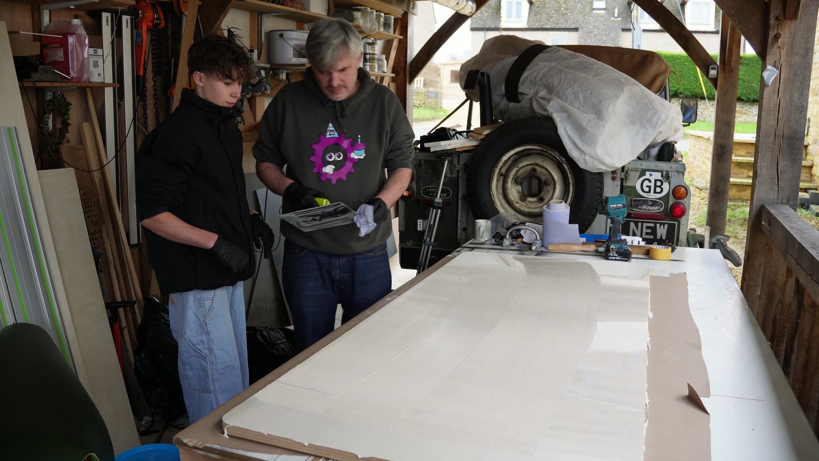 Daniel and his son checking the large white desk top on the workbench.