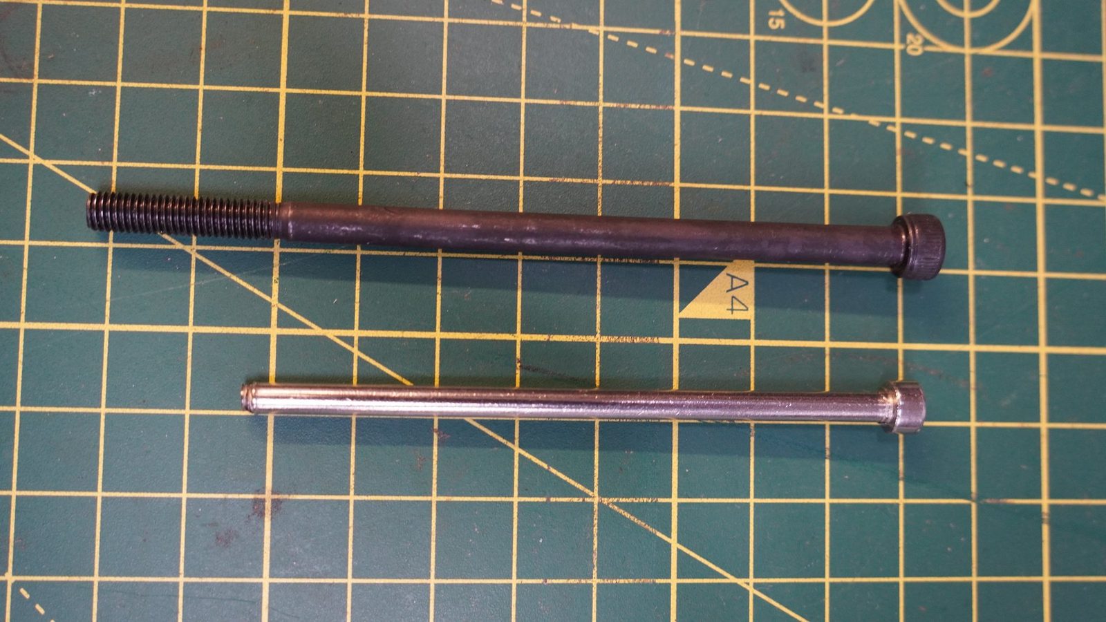 Robot arm rods and fasteners laid out on a cutting mat.