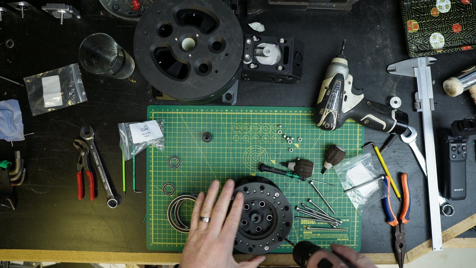Cycloidal reducer parts and tools laid out on a green cutting mat.