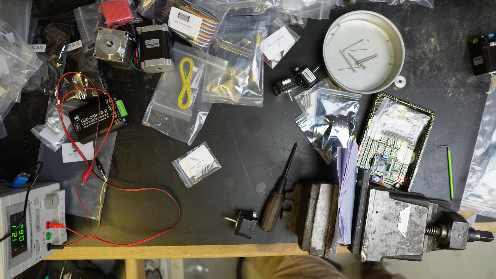 Robot arm motors, wires and parts spread across a workshop bench.