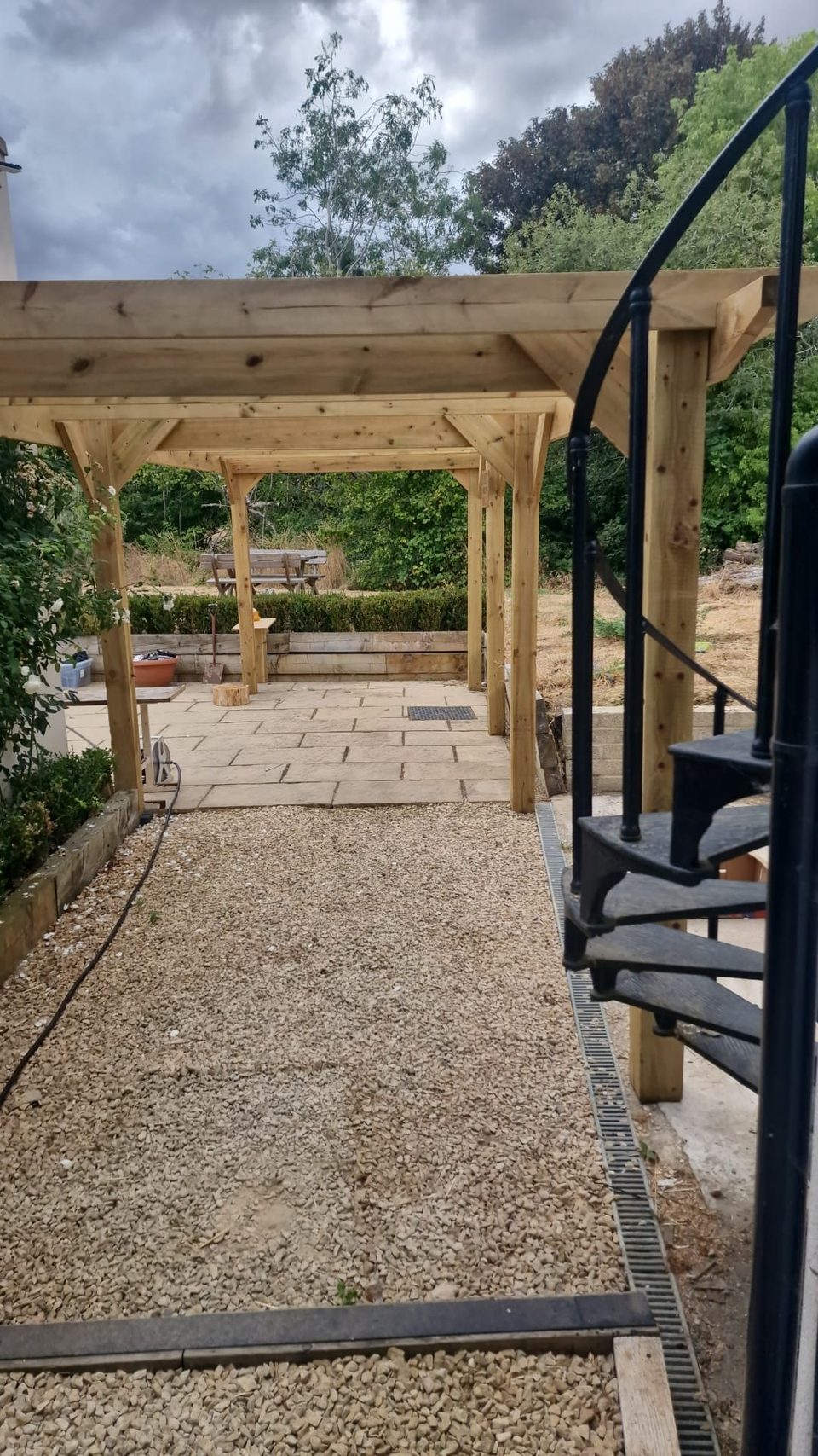 Finished spiral staircase beside timber pergola posts.