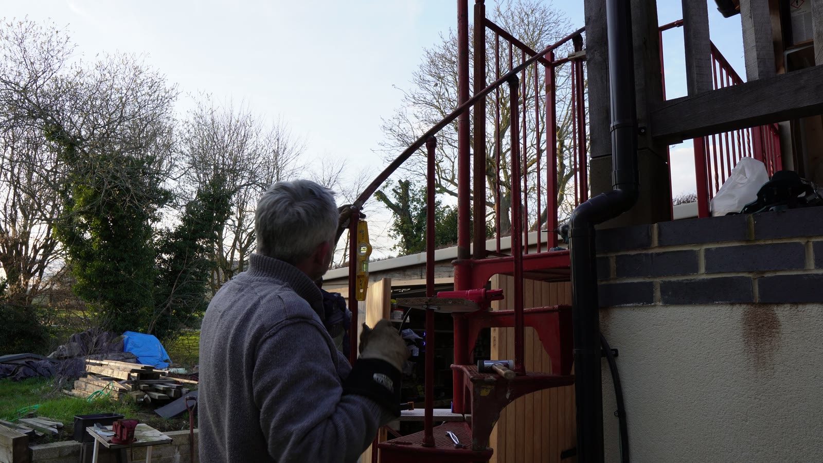 Daniel fitting spiral staircase steelwork outside the house.