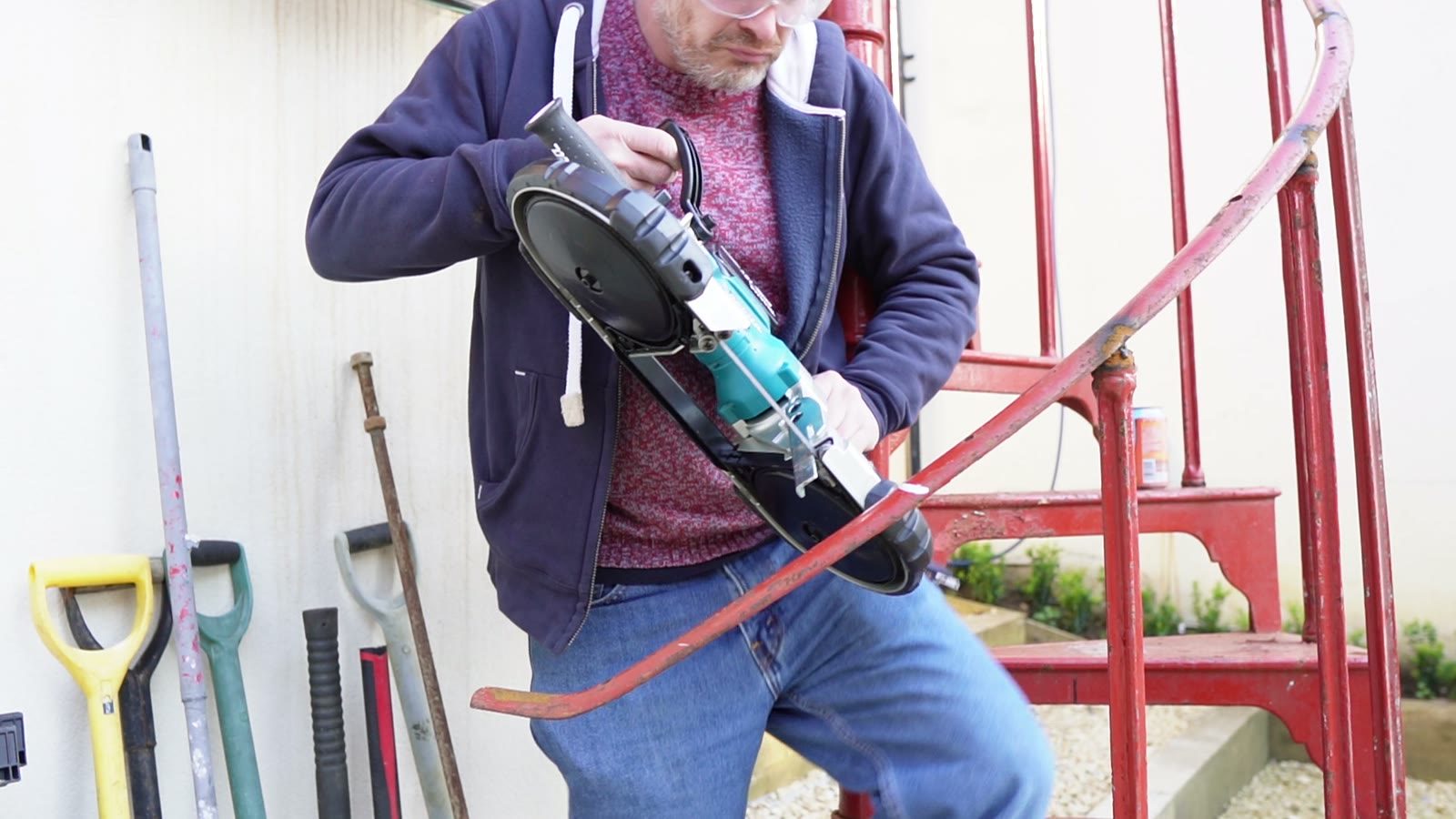 Close workshop view of a tool being used on a red stair component.