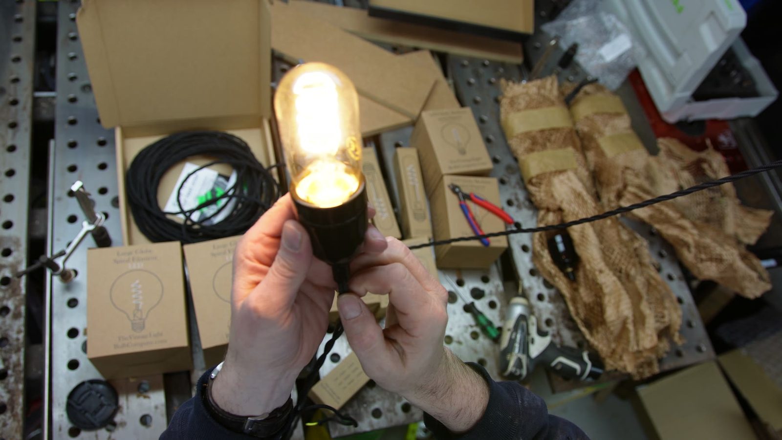 A lit vintage-style bulb holder being tested on the workbench.