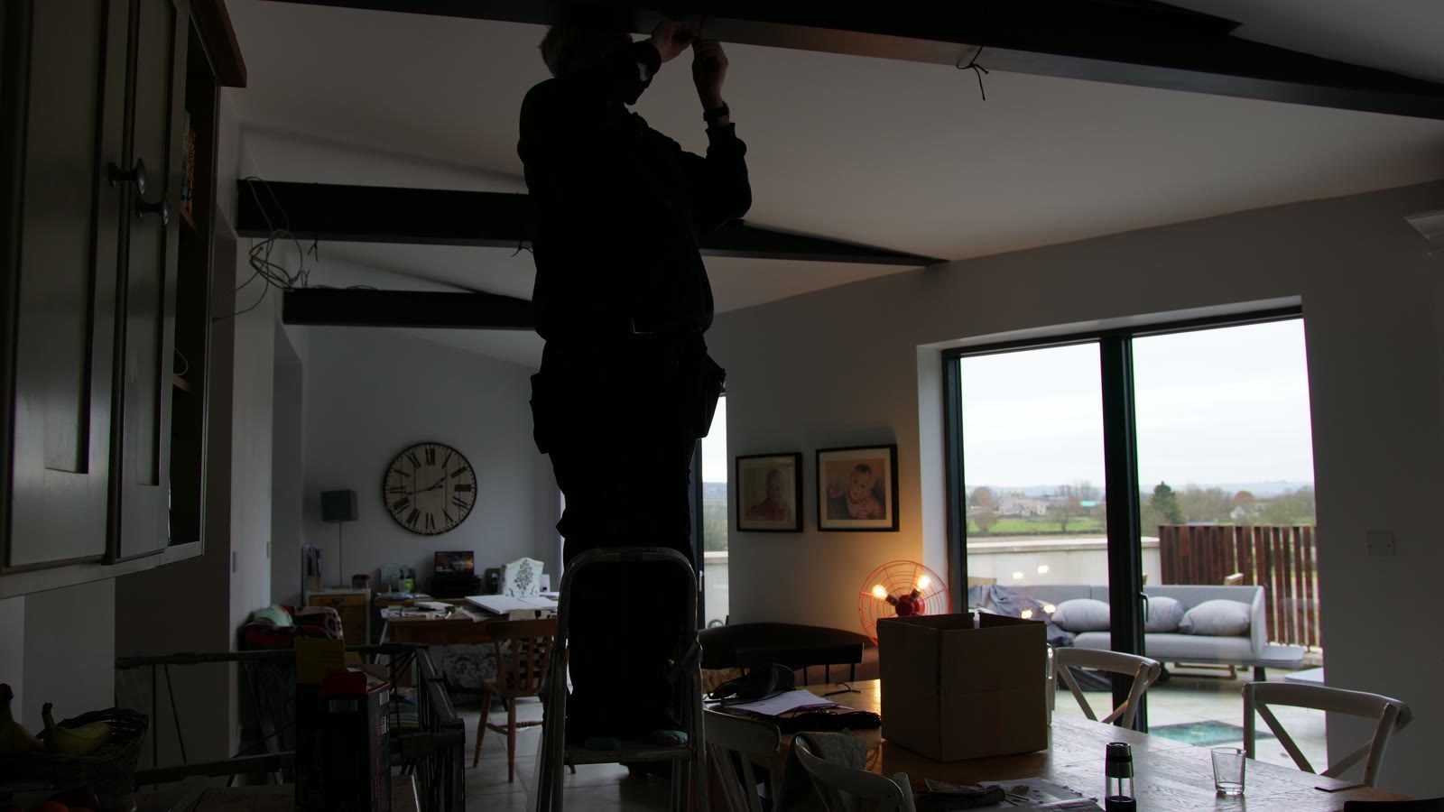 Daniel working high on a step ladder while installing the light run across the room.